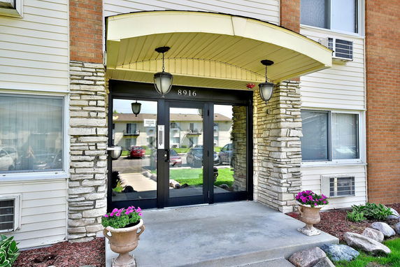 Front view of a building entrance with stone detailing and glass doors.