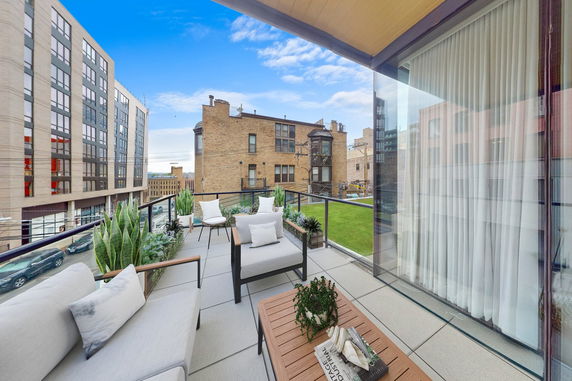 Rooftop patio with outdoor seating and plants, surrounded by buildings.