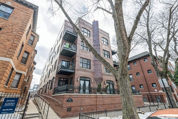 Front view of a multi-story brick apartment building with balconies.