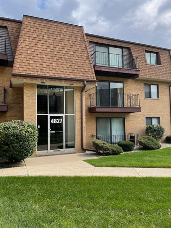 Front view of a multi-story apartment building with balconies and a pitched roof.
