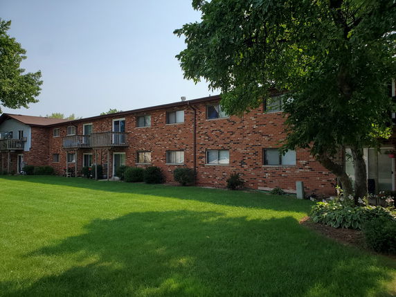 Front view of a two-story brick apartment building with balconies.