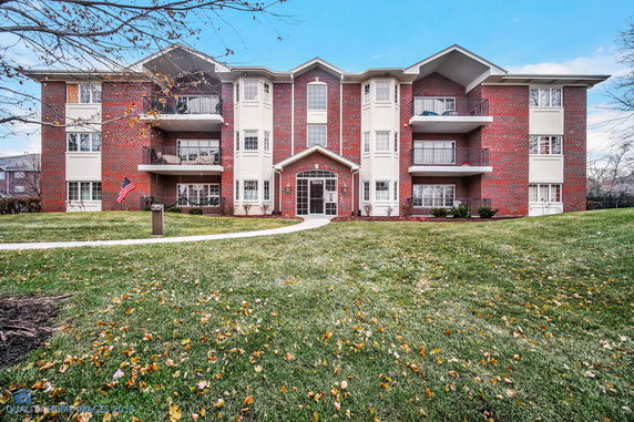 Front view of a three-story brick apartment building with balconies.