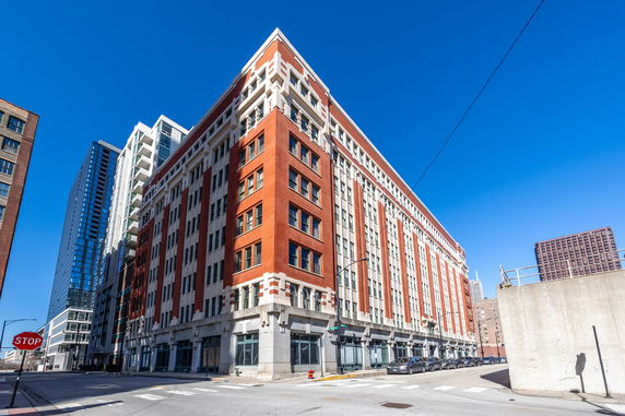Front view of a large multi-story brick building on a street corner.