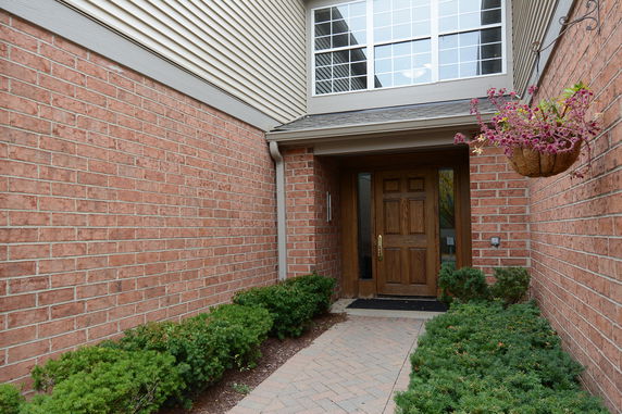 Entrance of a brick house with a wooden door and a window above.