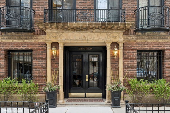 Front view of a brick building with decorative balconies and a double-door entrance.