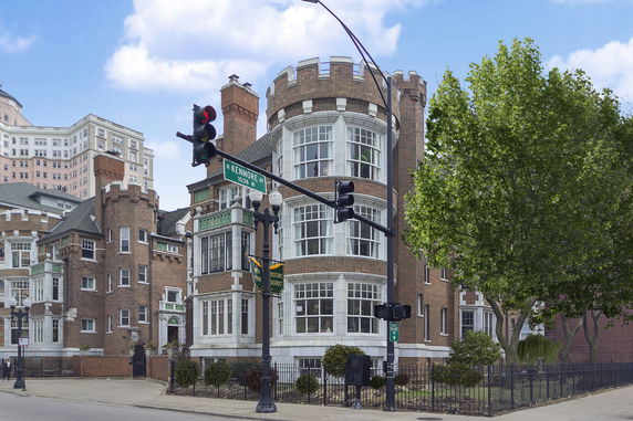 Front view of a historic building with a castle-like appearance, featuring bay windows and brick facade.