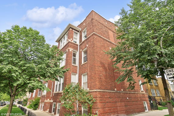 Front view of a multi-story brick building on a corner.