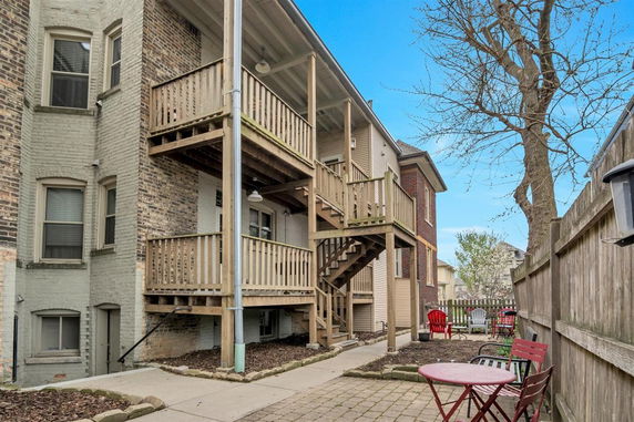 Back view of a brick building with wooden balconies and an outdoor seating area.