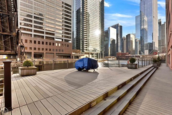 View of high-rise buildings and a river from a wooden deck.