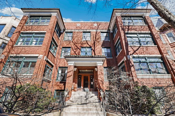 Front view of a multi-story brick building with large windows and an entry staircase.