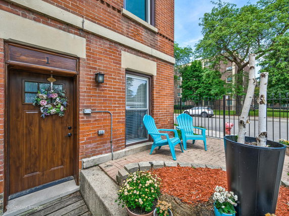 Front view of a brick building entrance with a wooden door and window.