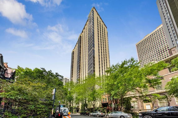 Tall multi-story building with a modern design, surrounded by trees and other buildings.