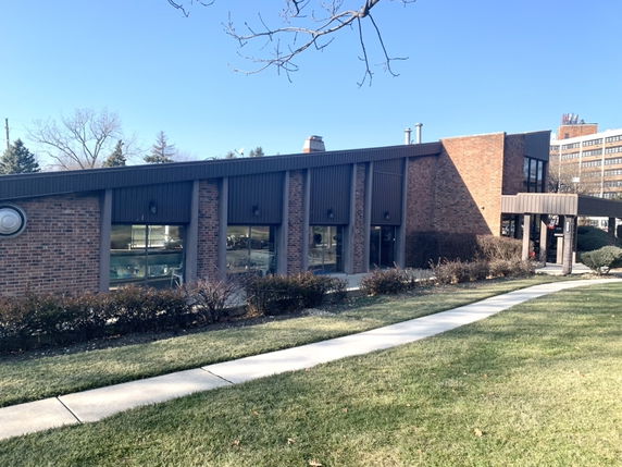Front view of a modern, flat-roofed building with large windows and brick façade.