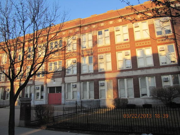 Front view of a multi-story brick building with large windows.