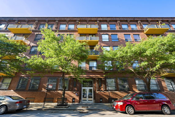Front view of a multi-story brick building with yellow balconies.
