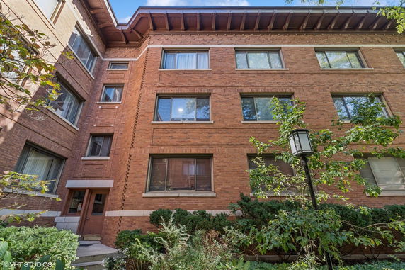 Front view of a multi-story brick building with large windows and a small entrance.