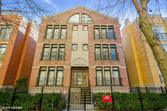 Front view of a multi-story brick building with multiple windows and a gated entrance.