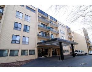 Front view of a multi-story apartment building with a covered entrance.