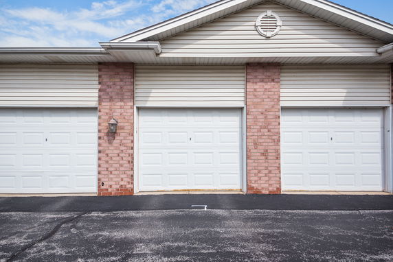 Front view of a building with three garage doors and brick facade.