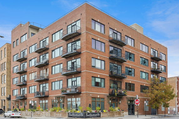 Front view of a multi-story brick apartment building with balconies.