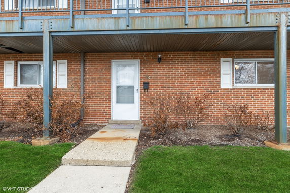 Front view of a brick building with a white door and windows on the ground floor.