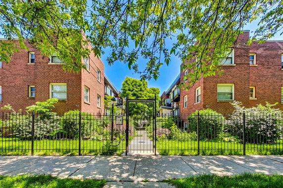 Front view of two-story brick residential buildings with a gated entrance.