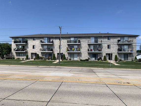 Front view of a three-story apartment building with multiple balconies.