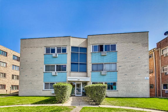 Front view of a three-story apartment building with blue and beige brick facade.