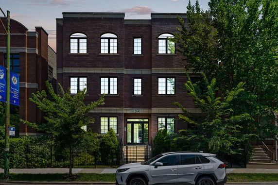 Front view of a three-story brick building with multiple windows.
