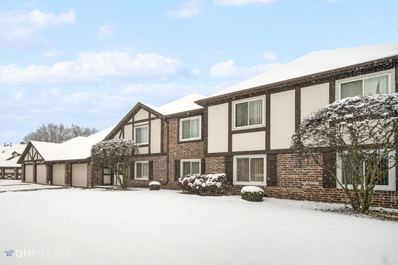 Front view of a snow-covered two-story building with Tudor architectural elements.