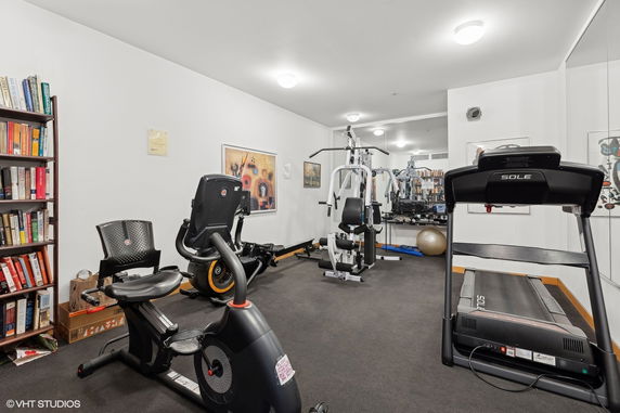 Home gym with exercise equipment and bookcase.
