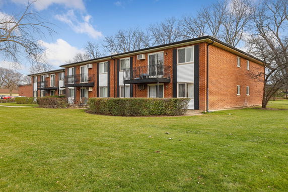 Front view of a two-story apartment building with brick facade and multiple balconies.