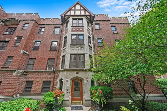Front view of a multi-story brick building with a decorative facade and arched entrance.