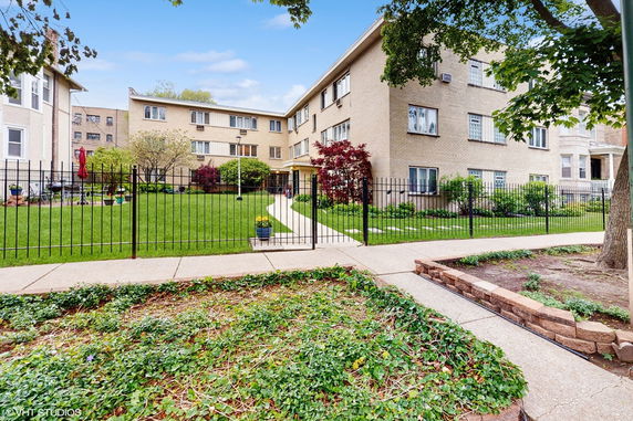 Front view of a multi-story apartment building with a fenced yard.