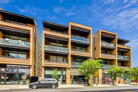 Front view of a modern multi-story building with balconies and large glass windows.