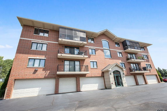 Front view of a multi-story brick apartment building with balconies.