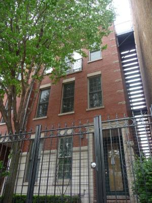 Front view of a multi-story brick building with metal fence and exterior staircase.