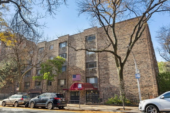 Front view of a multi-story brick apartment building with several windows and a covered entrance.