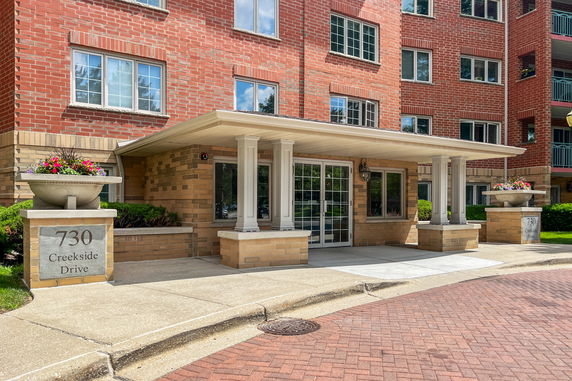 Front view of a multi-story building entrance with brick exterior and a covered walkway.