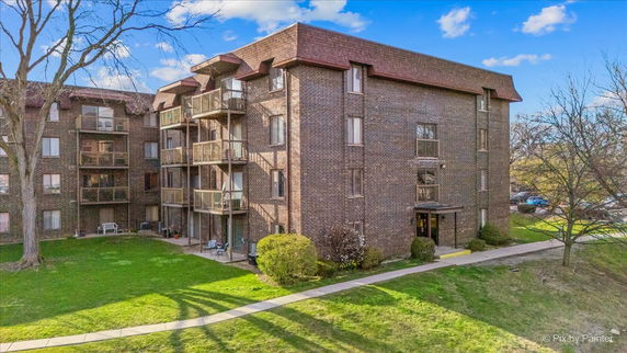 Front view of a multi-story brick apartment building with balconies.