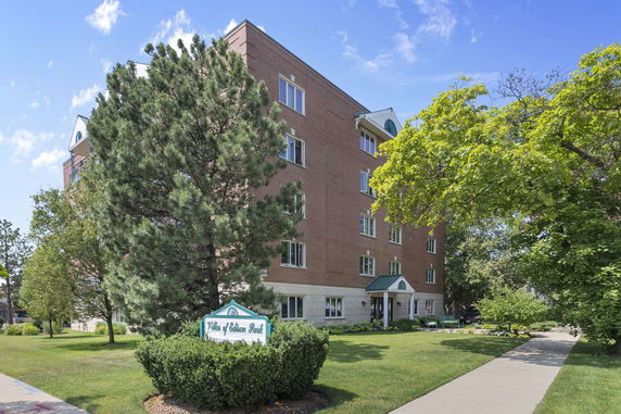 Front view of a multi-story brick building with several windows and a small entrance canopy.
