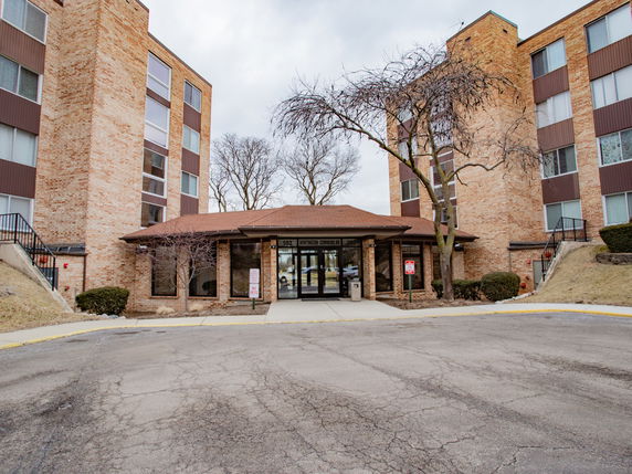Front view of a brick apartment building with multiple floors and a main entrance.