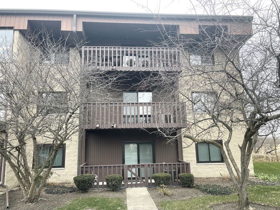 Front view of a multi-story building with balconies and a walkway.