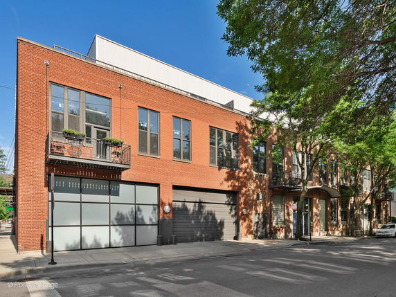 Front view of a two-story brick building with balconies and large windows.