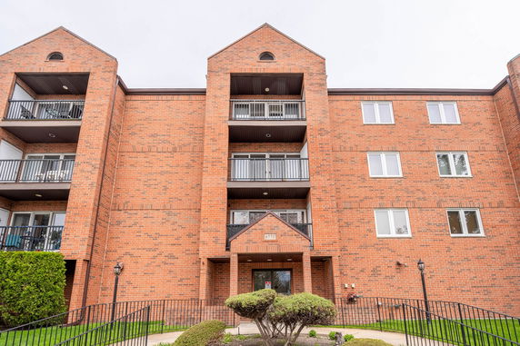 Front view of a multi-story brick apartment building with balconies.