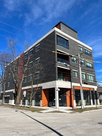 Front view of a modern multi-story building with large windows and brick facade.
