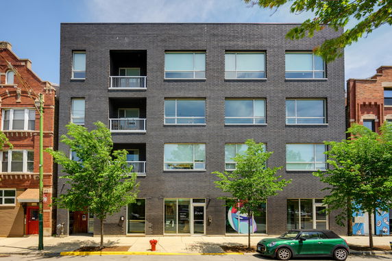 Front view of a modern four-story building with large windows and balconies.