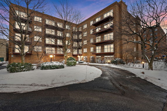 Front view of a multi-story brick building with balconies and a snow-covered path.