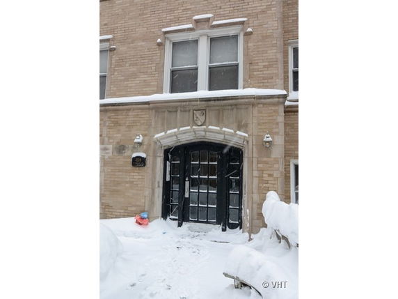 Front view of a snow-covered brick building with an arched entrance.