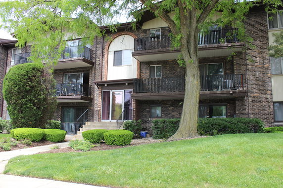 Front view of a multi-story brick apartment building with balconies.